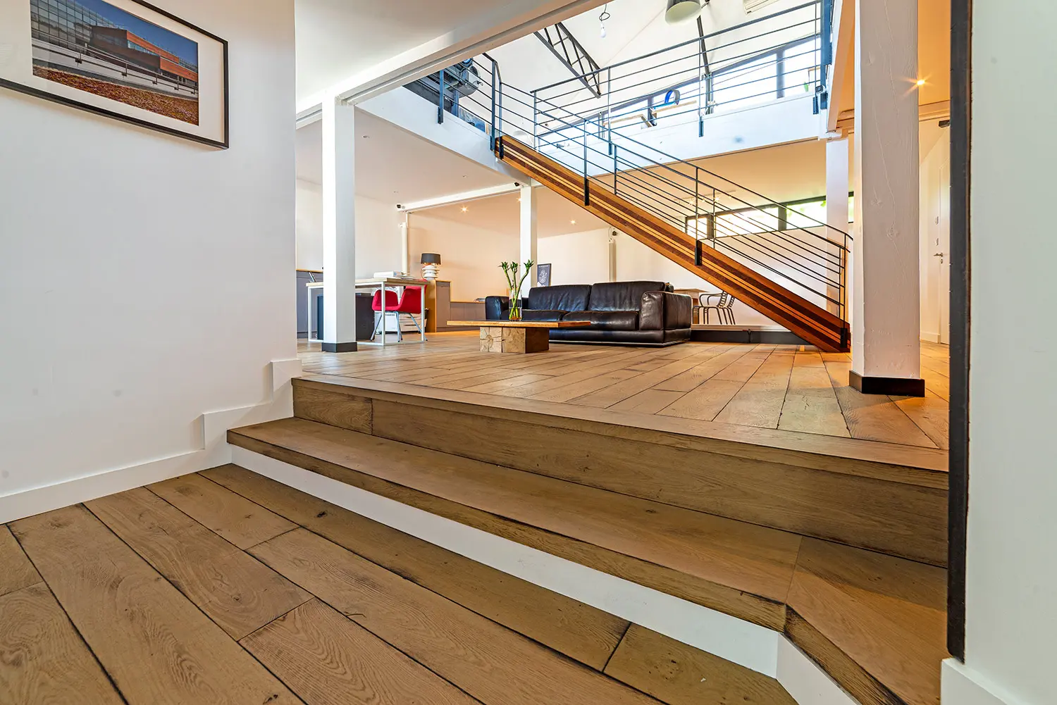 Estrade en chêne avec marches intégrées montant vers le salon du loft d'architecte